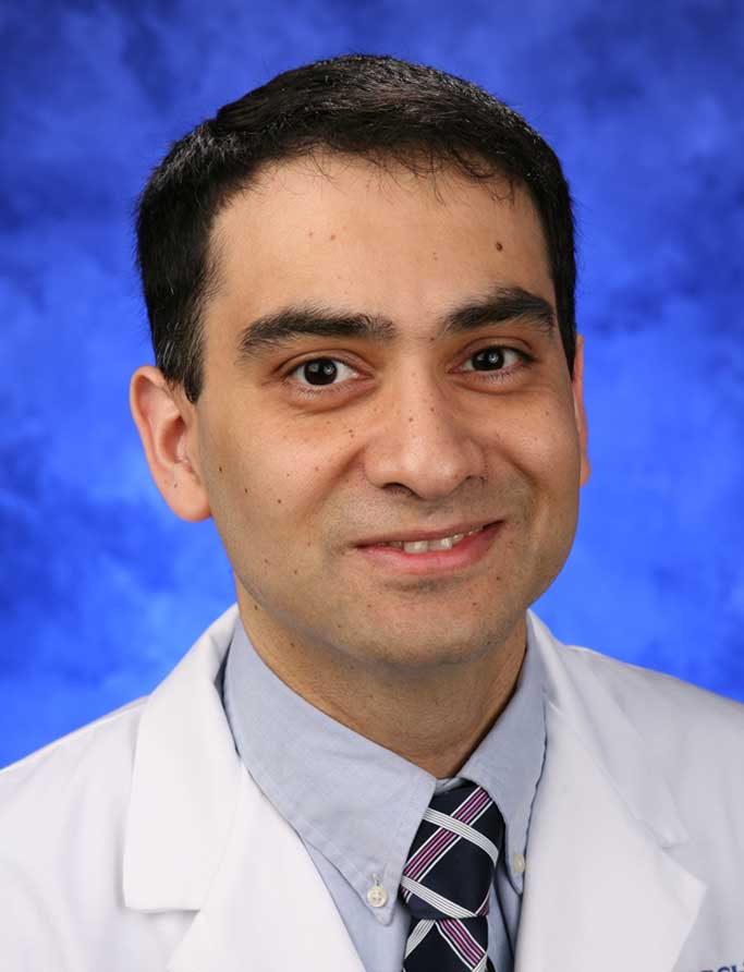 A portrait photograph of Dr. Aditya Joshi in front of a professional photo background.