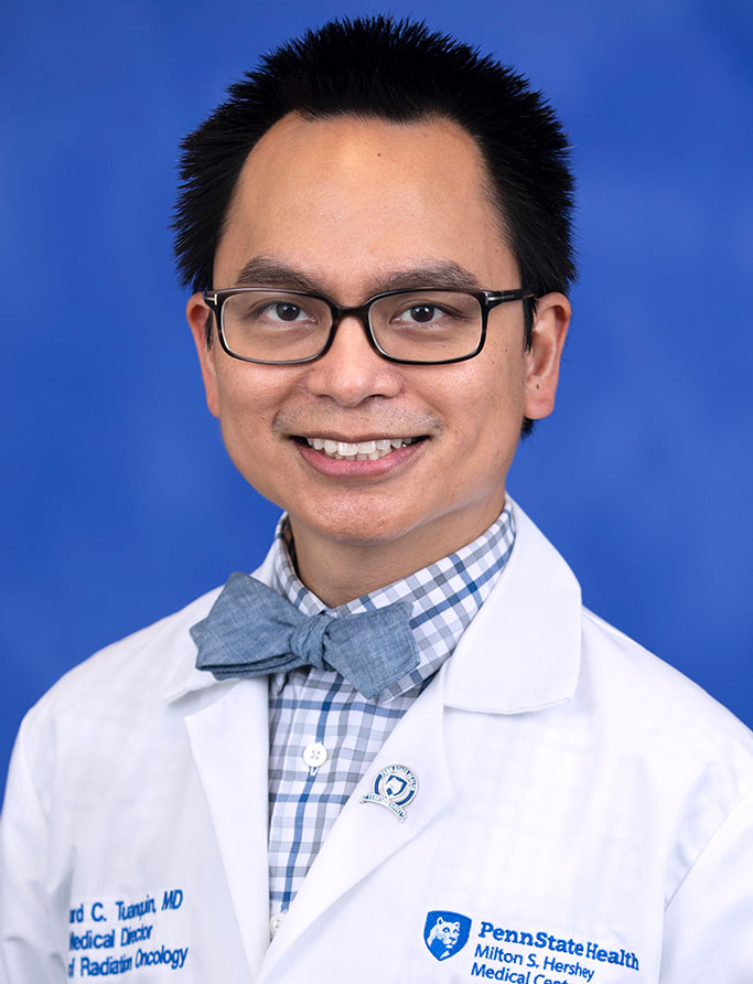 Leonard Tuanquin, MD, Interim Chair, Department of Radiation Oncology. He is pictured in a white medical coat against a blue background. 